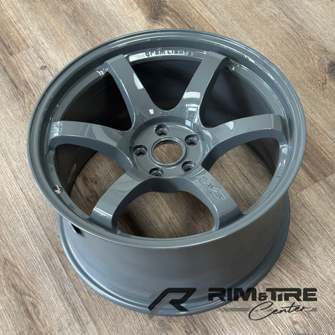 RAYS Gram Lights glossy gunmetal grey five-spoke car wheel with Made in Japan engraving resting on a light brown wooden floor