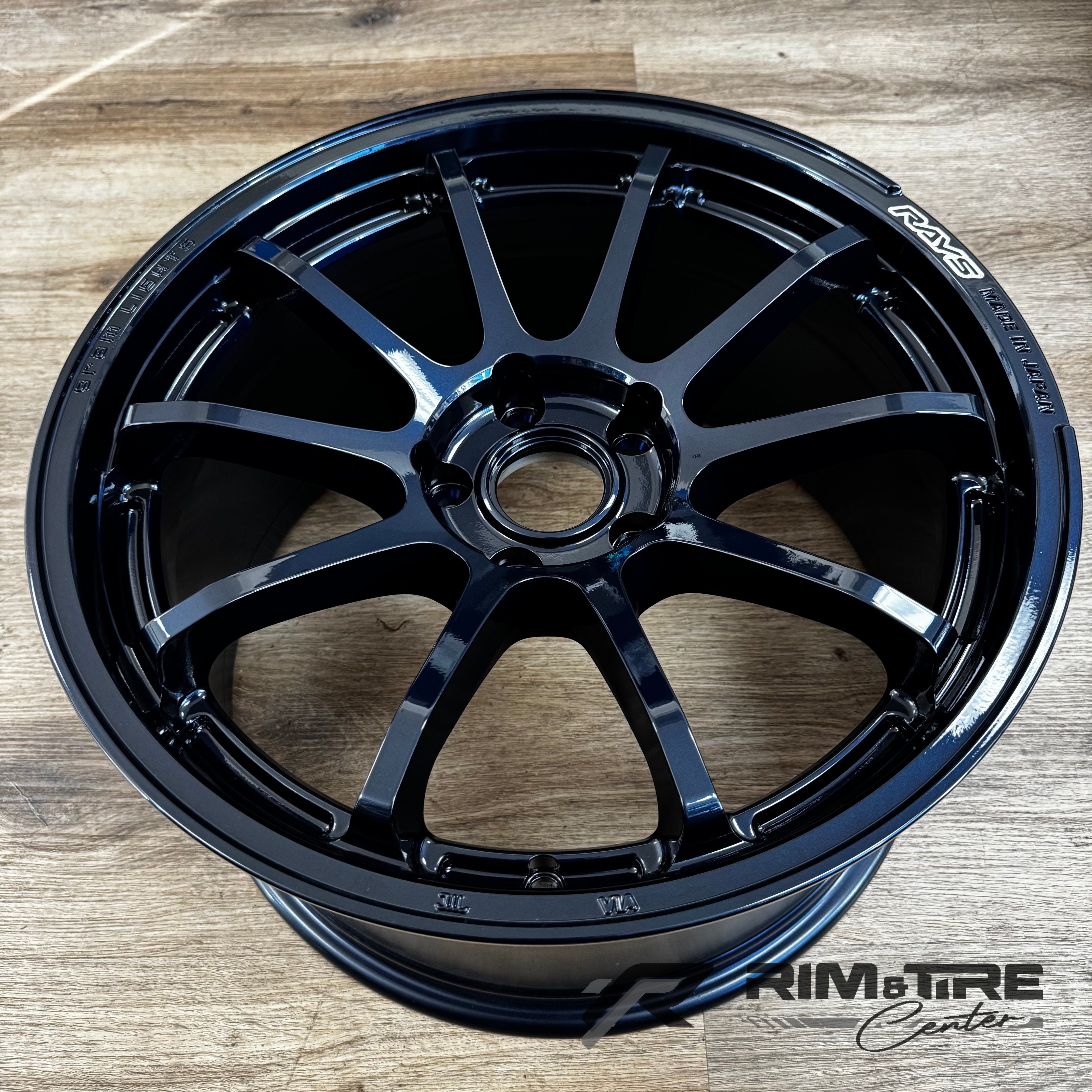 RAYS metallic car wheel on a light wood floor with a glossy dark finish, multi-spoke design, and RAYS MADE IN JAPAN branding
