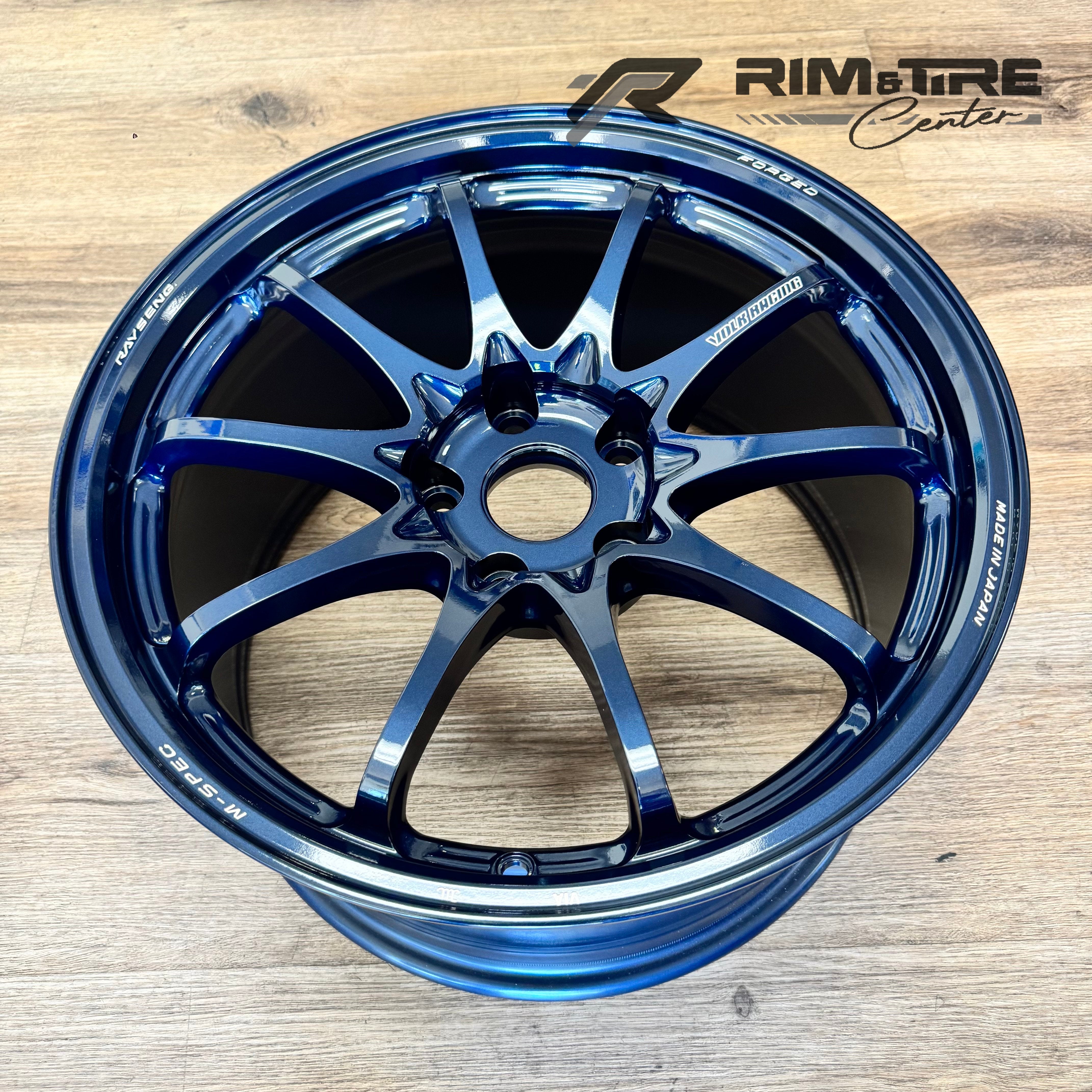 RAYS ENGINEERING VOLK RACING TE37 SAGA M-SPEC forged wheel rim in a stunning metallic blue finish displayed on a wooden floor highlighting its sleek multi-spoke design and Made in Japan inscription