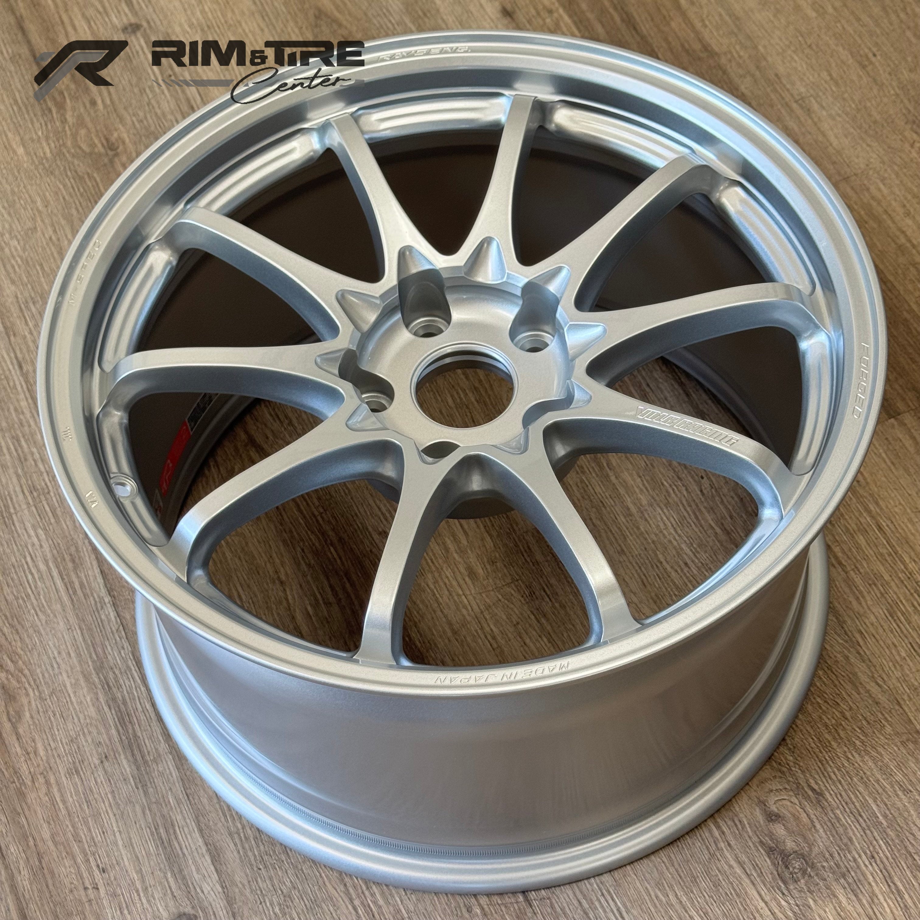 Photograph of a single silver RAYS ENG VOLK RACING forged ten-spoke car wheel on a wooden floor embossed with MADE IN JAPAN and a red inside label