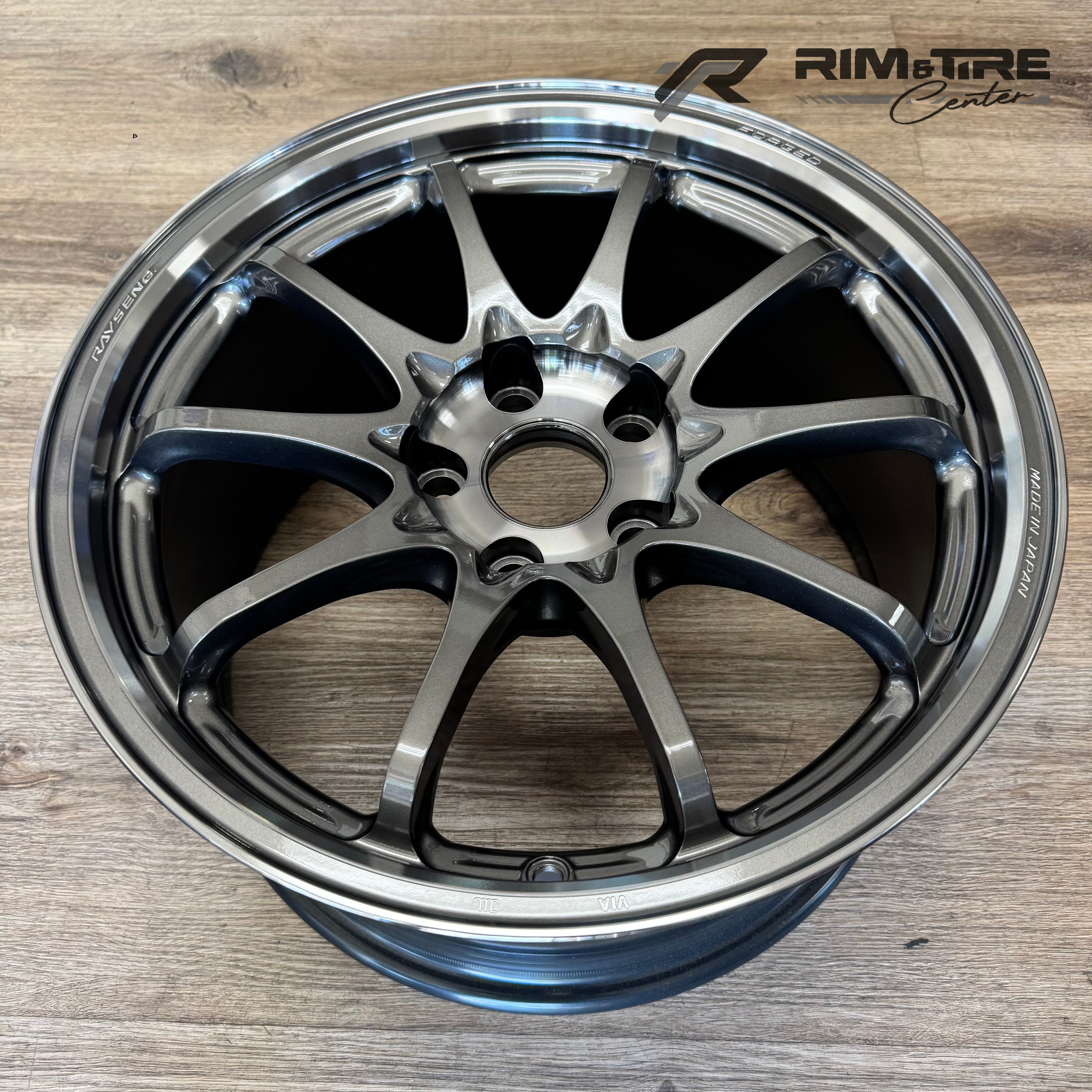 RAYS ENGINEERING forged gunmetal gray 10-spoke automotive wheel with a polished lip and Made in Japan inscription on a light wood floor