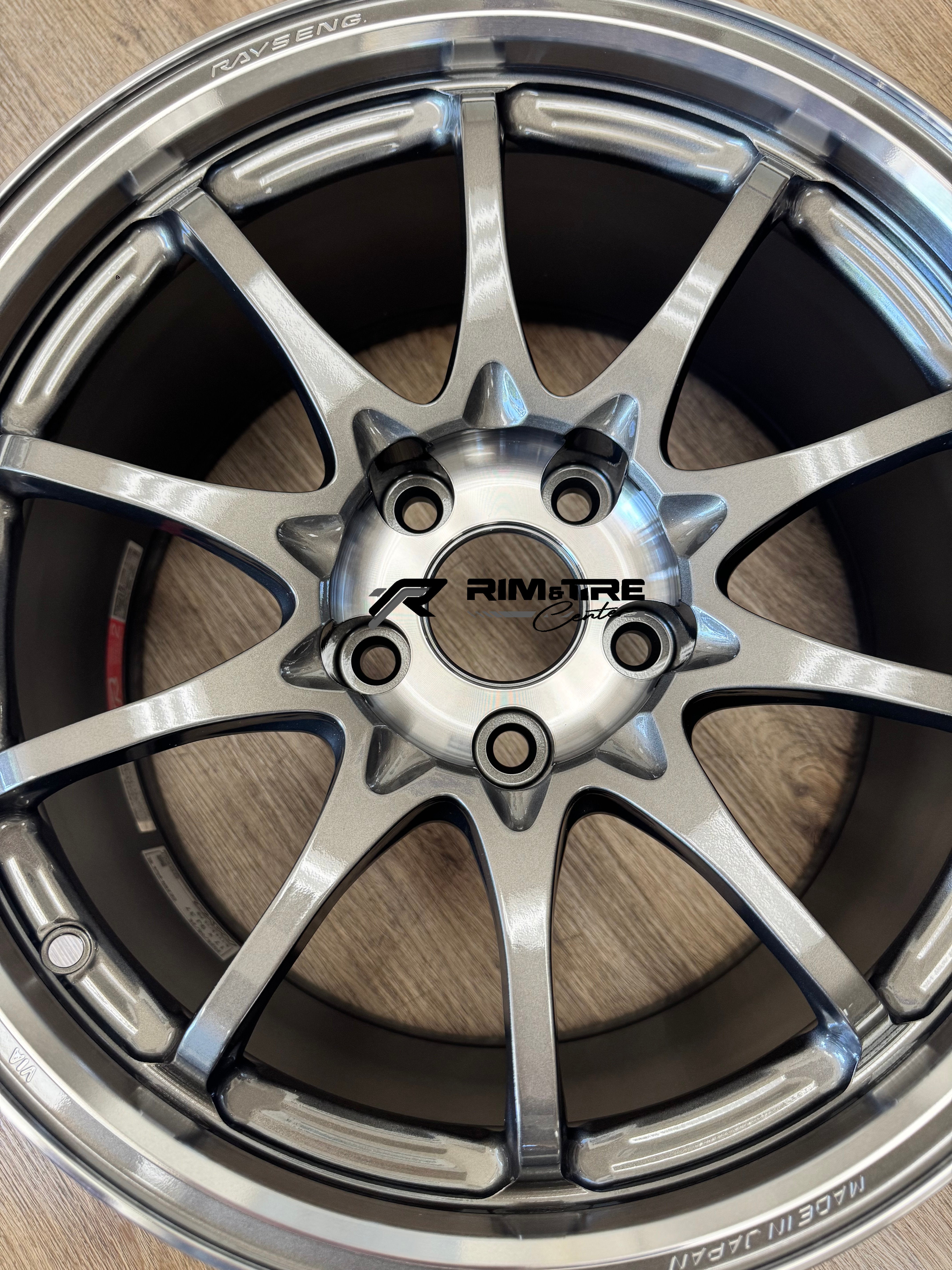 RAYS ENGINEERING multi-spoke wheel in glossy light silver finish displaying a 5-lug bolt pattern and MADE IN JAPAN etching on a light wood floor