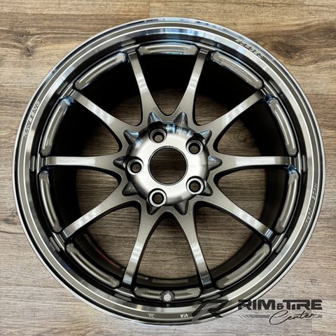 Photograph of a Rays Engineering forged gunmetal 10-spoke car wheel featuring a polished lip and 'RAYS ENG MADE IN JAPAN' branding, resting on a light wood floor