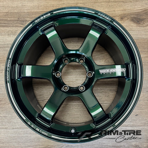 Forged RAYS Engineering Volk Racing wheel, a single deep glossy green six-spoke car rim, resting on a light brown wooden floor with distinctive "FORGED" and "MADE IN JAPAN" engravings and a bold silver "VOLK RACING" logo