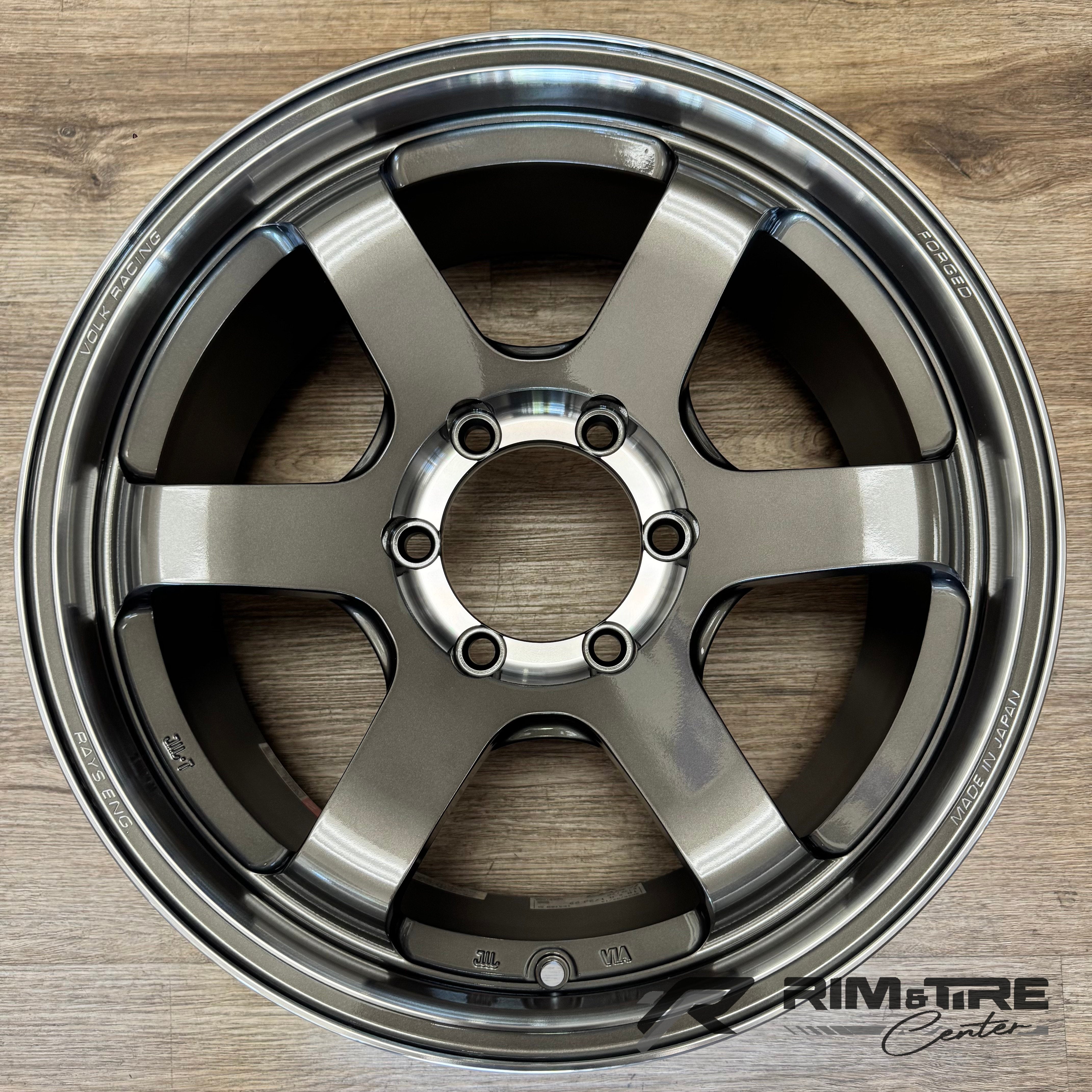 Product photo of a Volk Racing TE37 SL forged wheel in gunmetal gray with a 6-spoke design on a light wooden floor