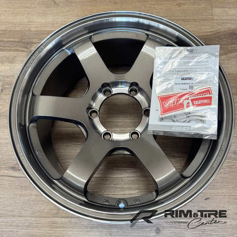 Rays Engineering Volk Racing TE37SL matte grey six-spoke wheel with a machined lip made in Japan resting on a wooden floor with a red and white sticker and manual set