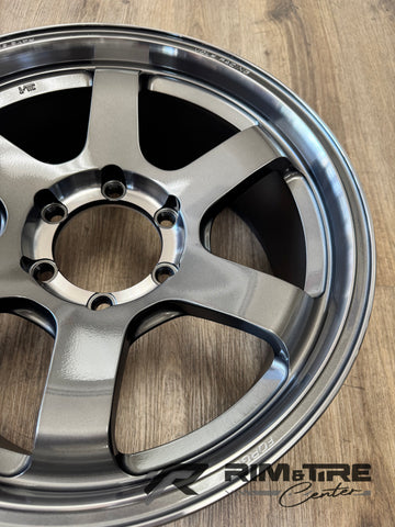 Product photo of a glossy silver Volk Racing TE37 six-spoke wheel resting on a wooden surface with embossed Rays Engineering and Volk Racing text
