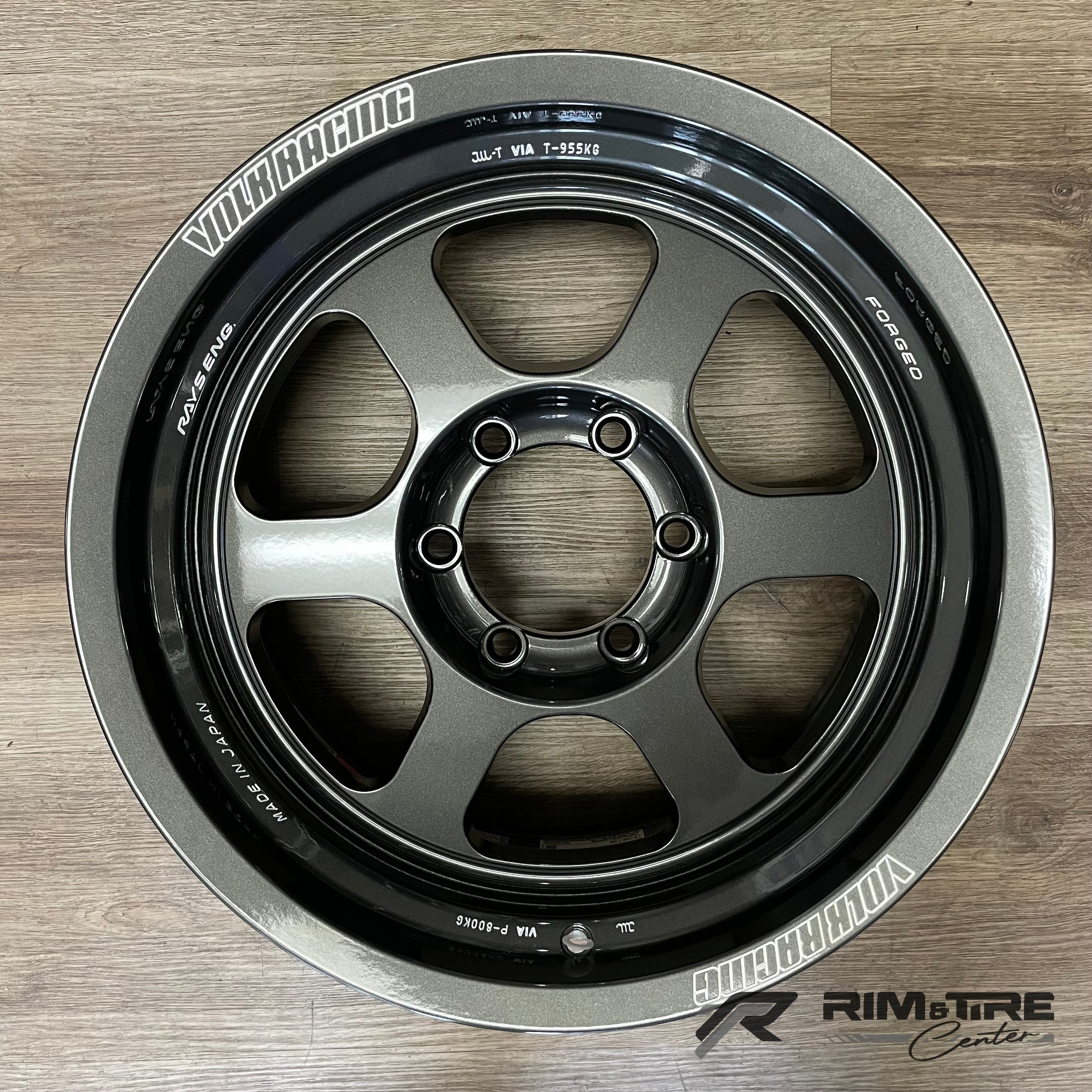 VOLK RACING RAYS ENG gunmetal forged six-spoke car wheel featuring white lettering for 'FORGED' and 'MADE IN JAPAN' on a wooden floor
